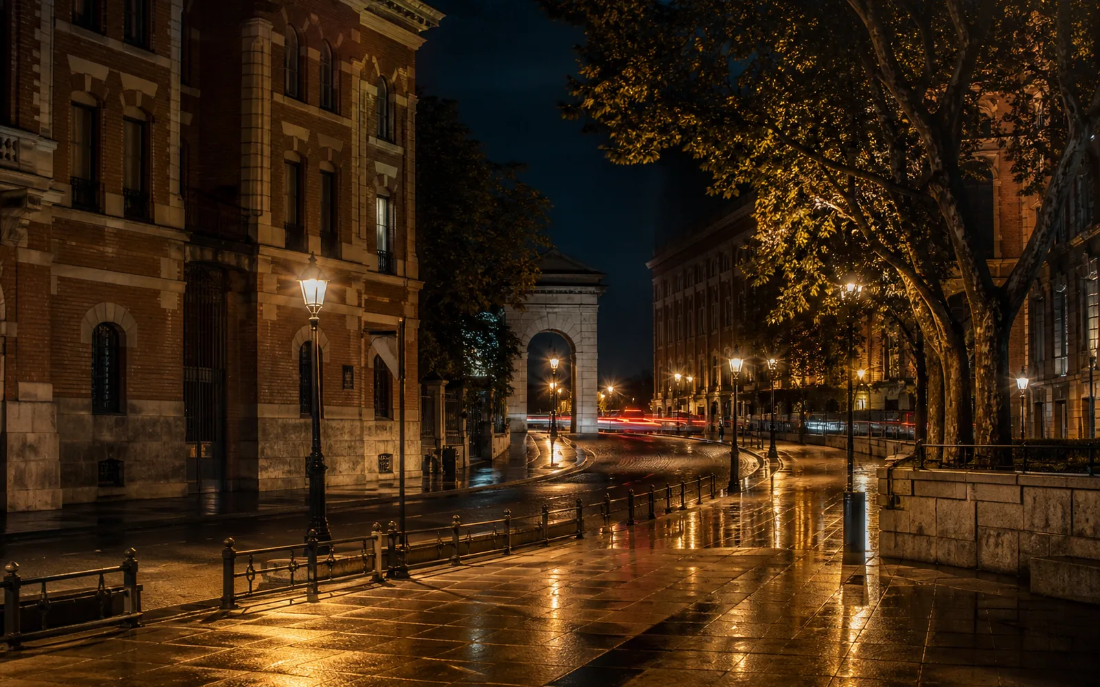 Calle de Madrid por la noche con farolas doradas y pavimento húmedo que refleja la luz
